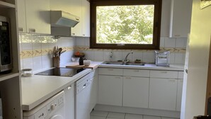 Eine kleine Küche mit integriertem Waschtrockner, Spüle und Fenster für natürliches Licht.