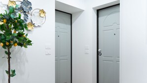 Un couloir avec deux portes, un paillasson et une plante aux feuilles vertes et aux fruits jaunes.