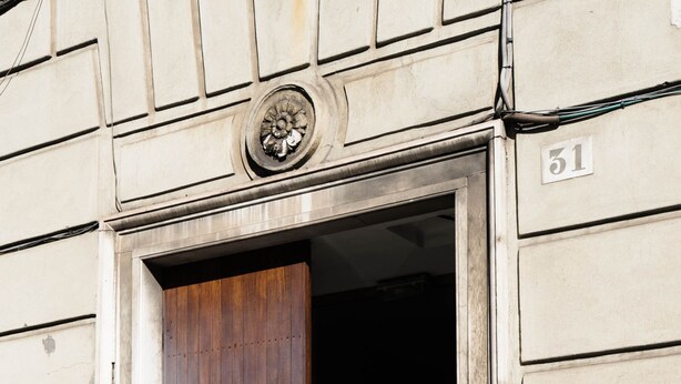 Une entrée d’immeuble avec une porte en bois, une sonnette en laiton et une plaque portant l’inscription « Studio Legal ».