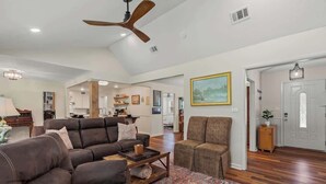 A spacious living room with a large brown sectional sofa, a smaller brown armchair, and a coffee table. A ceiling fan and recessed lighting are visible. - Magnolia Retreat 4BR 3BA Home (Hattiesburg)