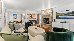 Un salon moderne avec une cheminée, un coin repas et une cuisine en arrière-plan.