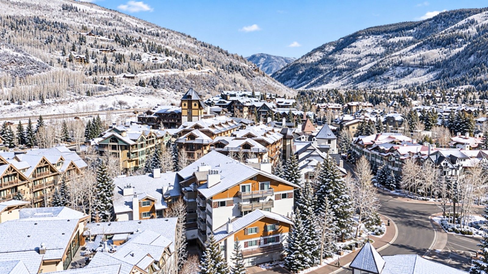 A resort with multiple buildings, including lodges and cabins, surrounded by snow-covered trees and mountains.