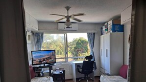 A compact hotel room with a bed, a desk, a chair, a television, and a ceiling fan. - Charming 1 and a half-bedroom apartment in beautiful Punta del Este. 4 people (Punta del Este)