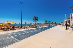 A beachside promenade with sun loungers, a clear blue sky, and a paved walkway. - Adriatic Seaview Suites by PS (Durrës)