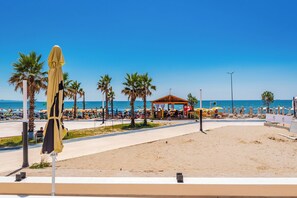 A beach with a covered seating area, palm trees, and a clear blue sky. - Adriatic Seaview Suites by PS (Durrës)