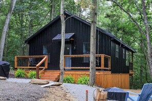 Eine Holzhütte mit einer Holzterrasse, einer kleinen Veranda und einem Solarmodul auf dem Dach.
