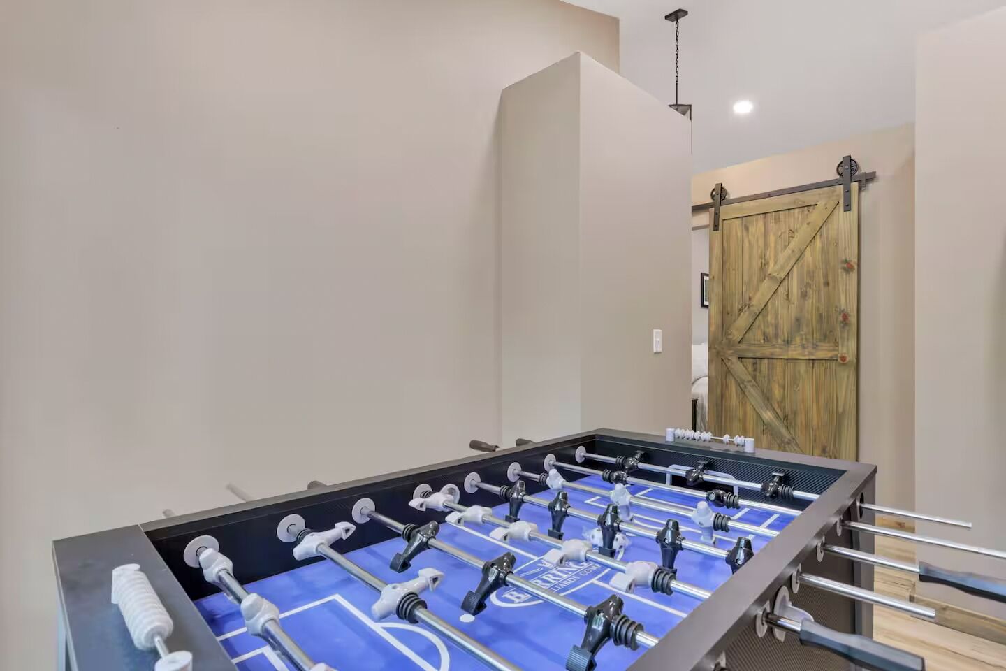 A foosball table in a room with a wooden door and a light fixture on the ceiling.