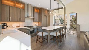 Een moderne keuken met houten kastjes, een centraal eiland en hangende lampen.