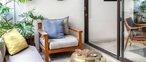 A modern living room with a sofa, a wooden chair, and a round table with decorative items.