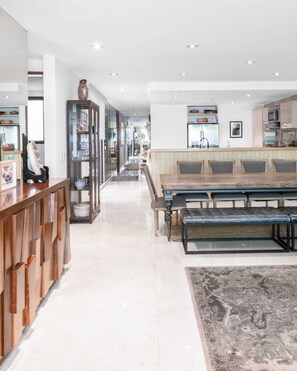 A modern kitchen with built-in appliances, a dining area with a long table and benches, and a hallway with glass-fronted cabinets. - Casa Gama Vicente | Art and Good Taste in Polanco (Ciudad de México)