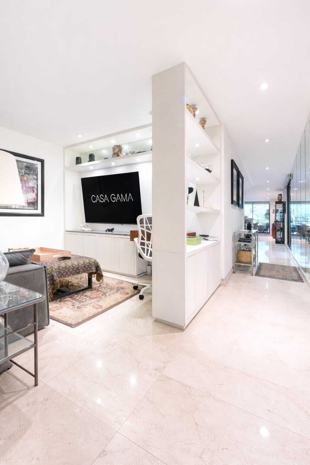 Un salon moderne avec un téléviseur à écran plat, une table basse en verre et un canapé.