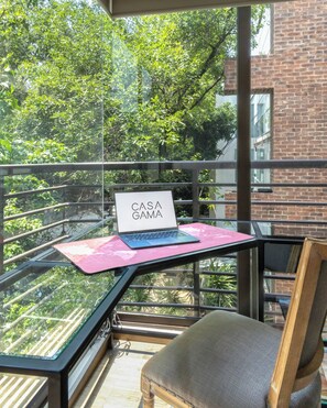 A balcony with a laptop on a pink mat, a chair, and a glass railing. - Casa Gama Vicente | Art and Good Taste in Polanco (Ciudad de México)