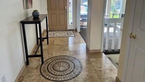 A hallway with a tiled floor, a door, a small table with a vase, and a view of a balcony. - Columbia View Retreat, Spacious Furnished Home in Argay Terrace,Portland Airport (Portland)