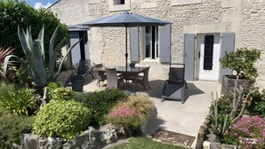 A stone building with a patio, outdoor furniture, and a variety of plants.