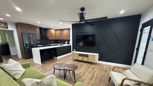 Un soggiorno moderno con un divano verde, un tavolino in legno e una TV montata su una parete d'accento nera.