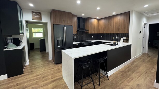 Una cucina moderna con isola centrale, sgabelli neri e mobili in legno.