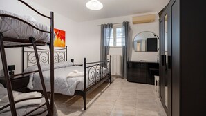 Ein Schlafzimmer mit Etagenbetten, einem Schreibtisch, einem Spiegel und einem Kleiderschrank.
