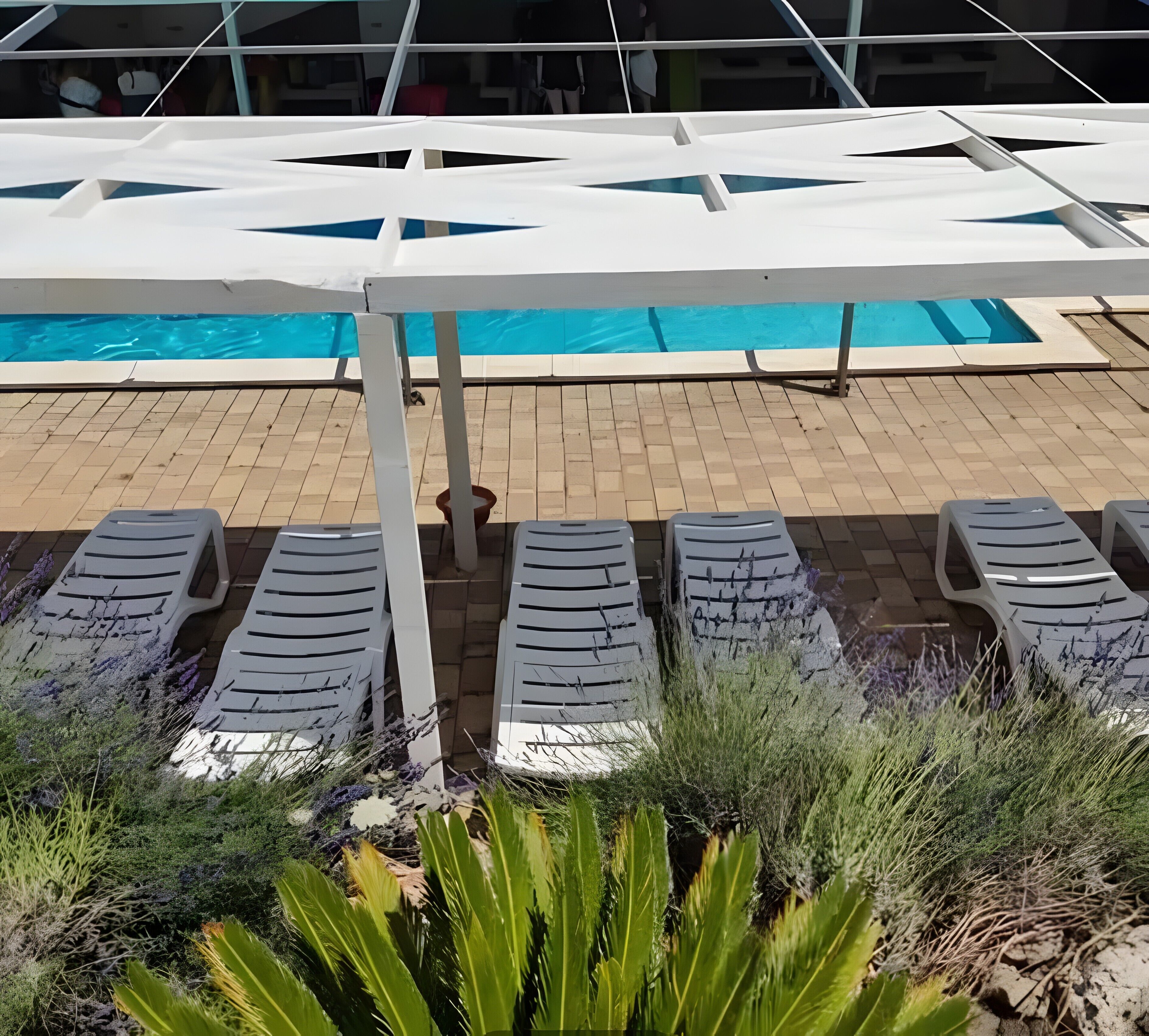 Uma área à beira da piscina com espreguiçadeiras e piscina.