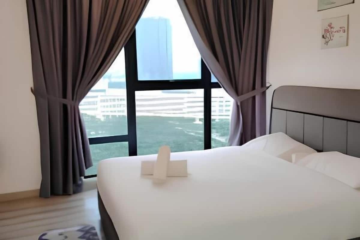 A hotel room with a bed, curtains, a window with a view of buildings, and a headboard.