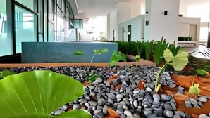 A modern indoor space with a reception area, a water feature with rocks and plants, and a view of the outdoors. - City View Southkey 2BR 2FREE 18F By Natol (Plentong)