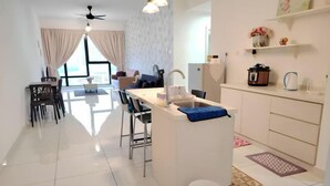 A modern kitchen with a central island, a dining area with chairs, and a view of the living room. - City View Southkey 2BR 2FREE 18F By Natol (Plentong)