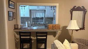 Una cocina compacta con ventana, dos sillas, una pequeña mesa de comedor y un sofá.