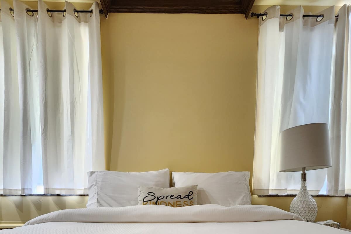 A neatly made bed with a pillow that reads "Spread Kindness."