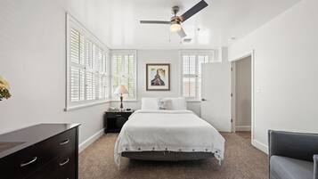 A bedroom with a bed, a nightstand, a dresser, and a ceiling fan.