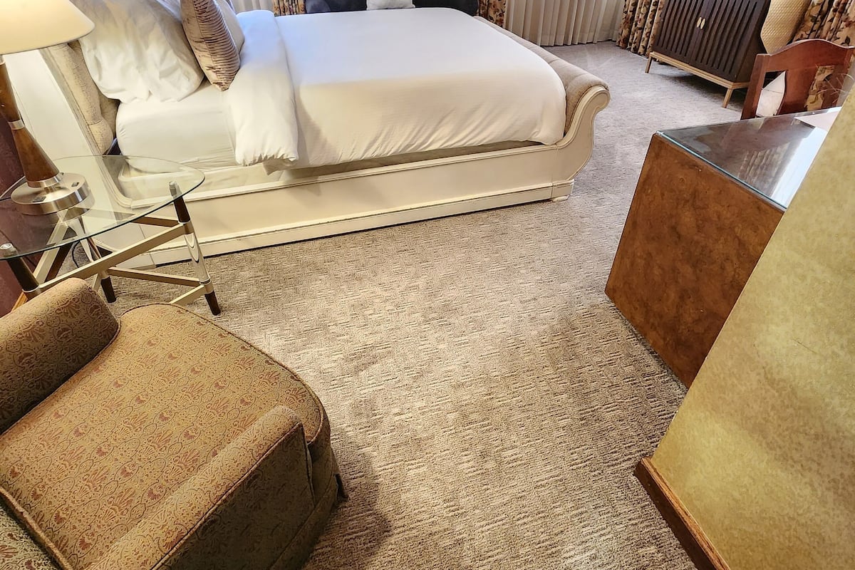 A hotel room with a large bed, a sofa, a small table, and a TV.