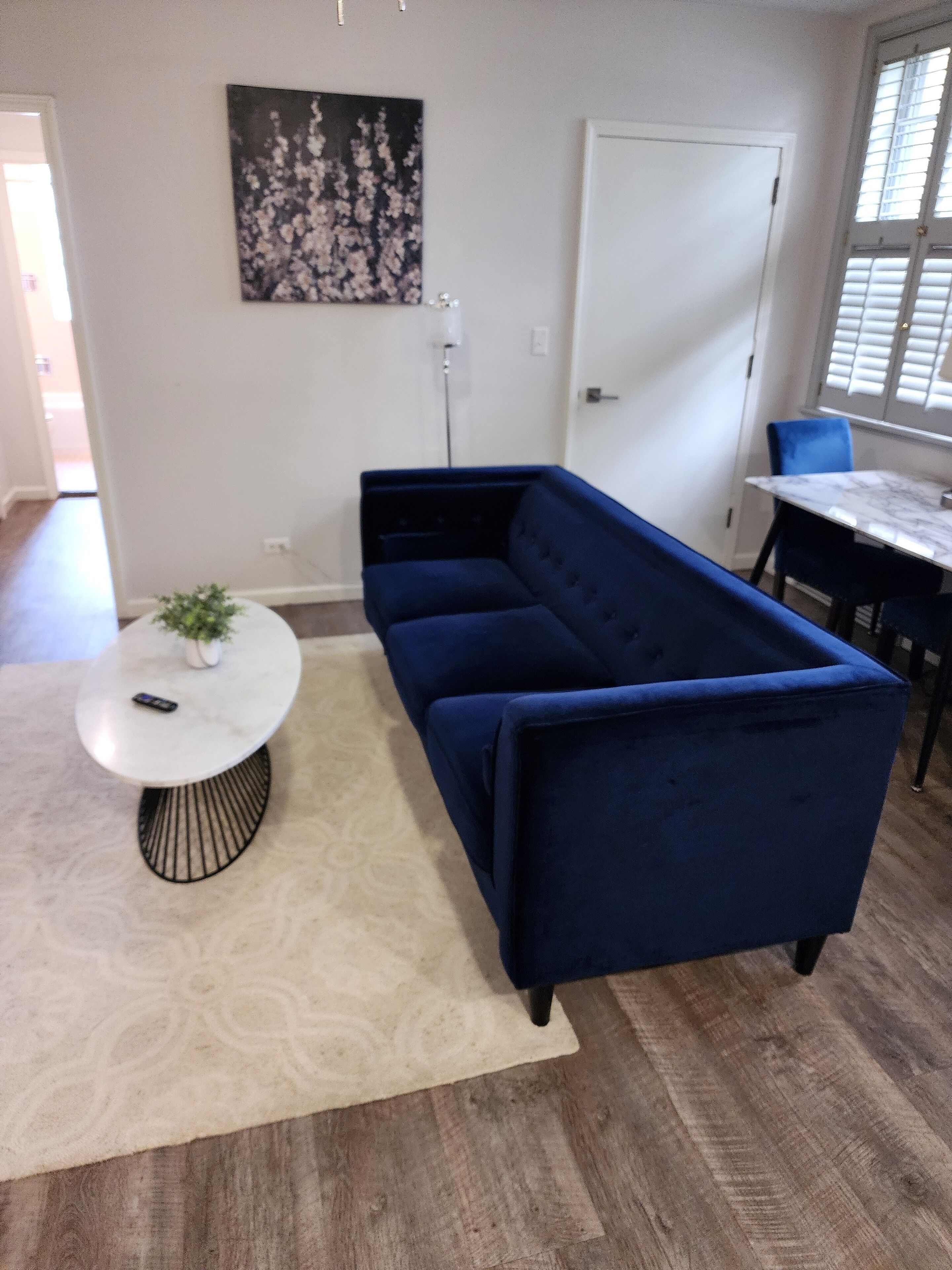 A modern living room with a dark blue sofa, a round coffee table, and a white door.