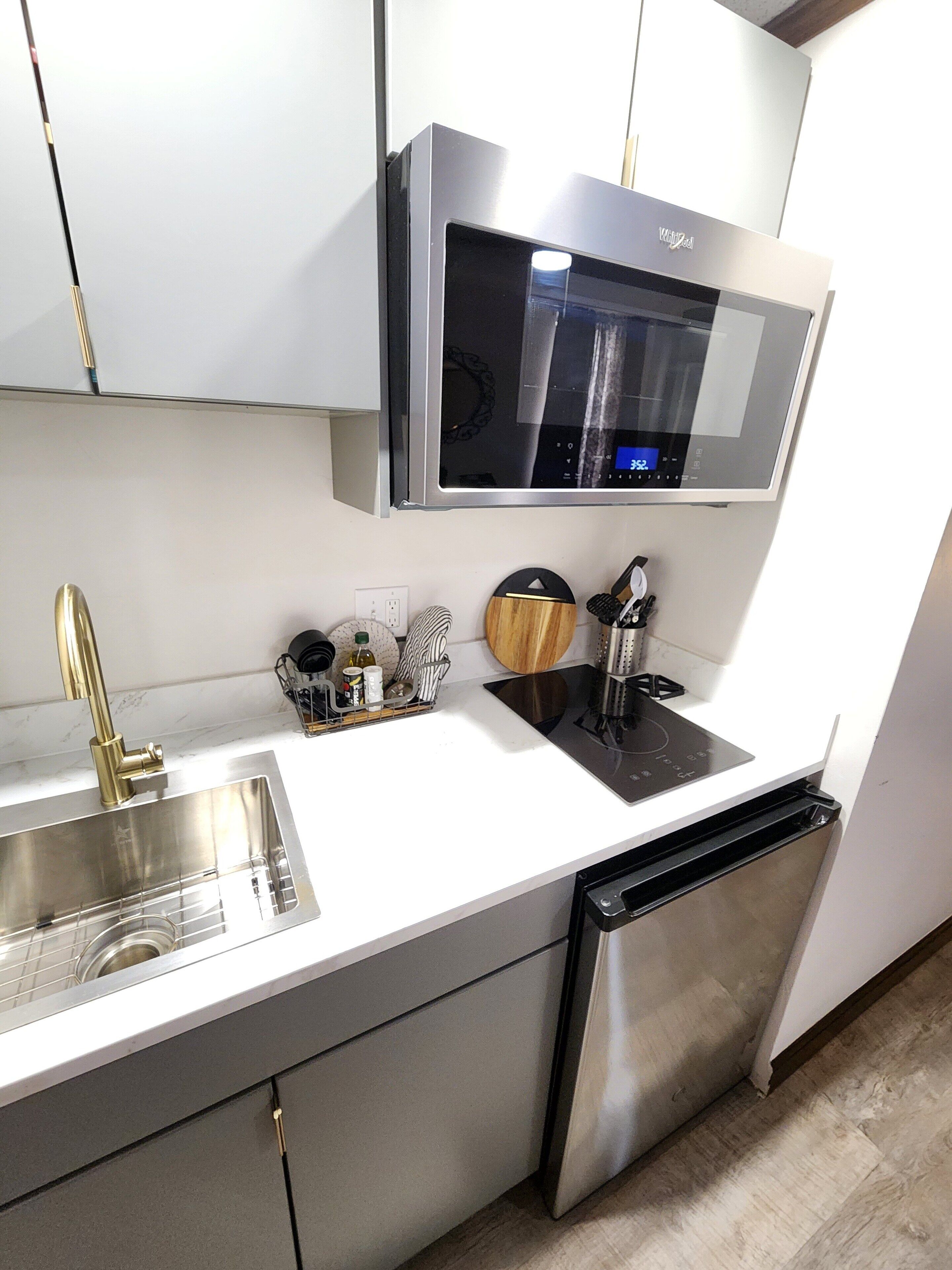 A modern kitchen with a stainless steel sink, a built-in dishwasher, a microwave, and a gas stove.