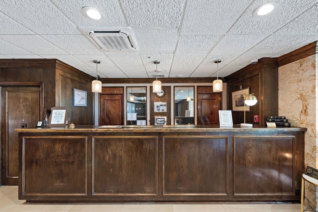 A reception desk with a wooden finish, multiple pendant lights, and framed pictures on the wall.