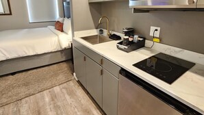 Cocina compacta con microondas integrado, lavamanos y estufa. Una ventana pequeña proporciona luz natural.