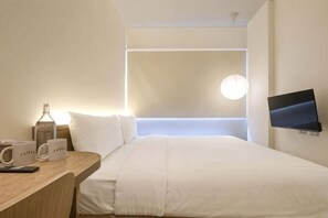 Une chambre d’hôtel avec un lit, un bureau avec une lampe, une télévision et une fenêtre donnant sur un beau paysage.