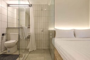 Une salle de bain d’hôtel avec des toilettes, une douche et un lit.