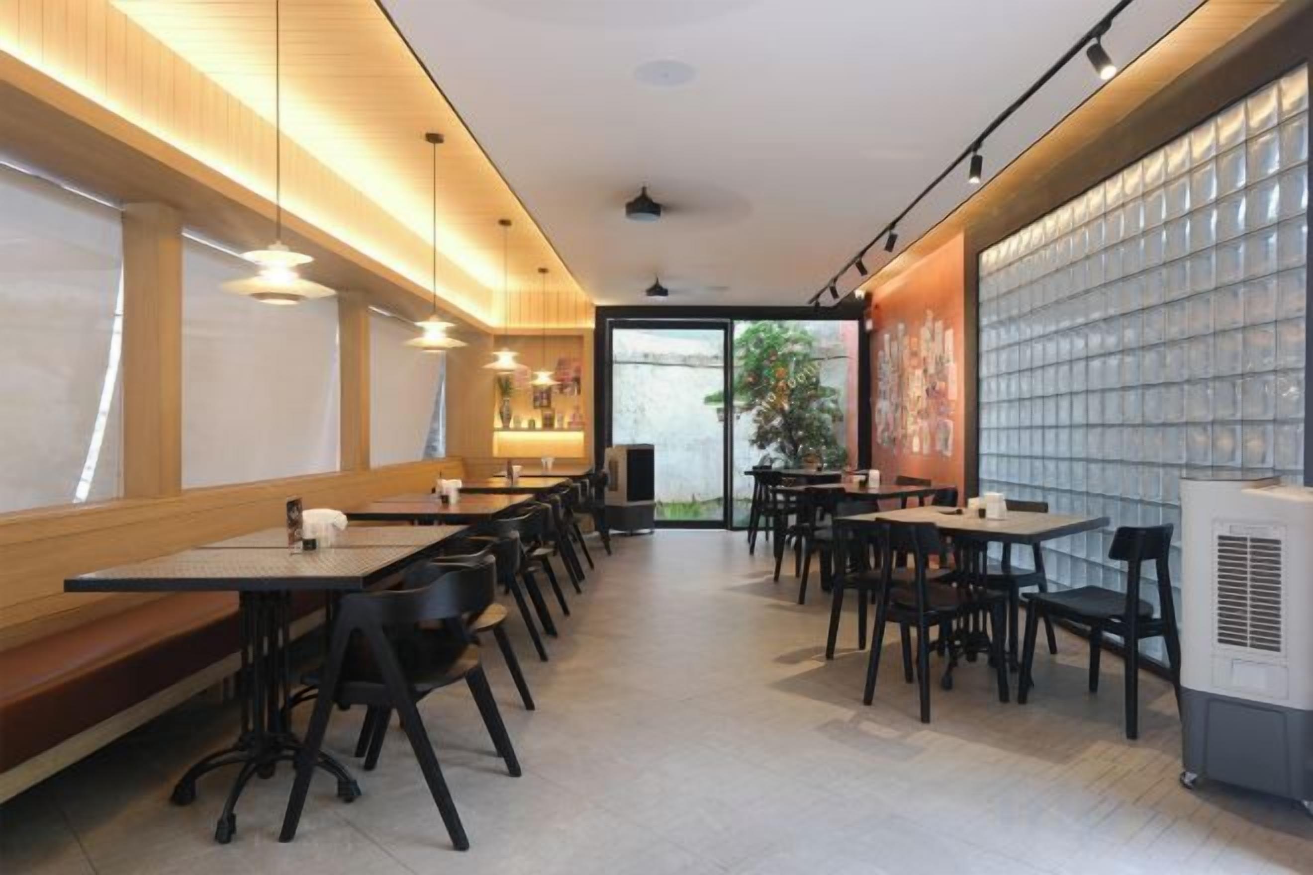 A restaurant interior with multiple tables and chairs, a counter, and a view of the outdoors.