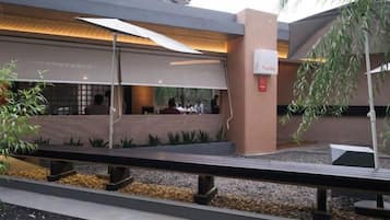 An outdoor seating area with tables and chairs, a covered walkway, and a building with a modern design.