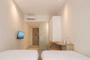 A modern hotel room with two beds, a TV, a desk, and a bathroom visible through a glass door. - Teduh Simatupang (South Jakarta)