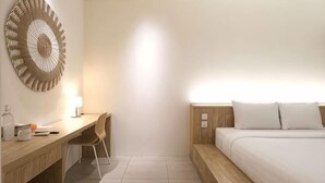 Una camera d'albergo con un letto, una scrivania, una sedia, una lampada a parete e un elemento decorativo a parete.