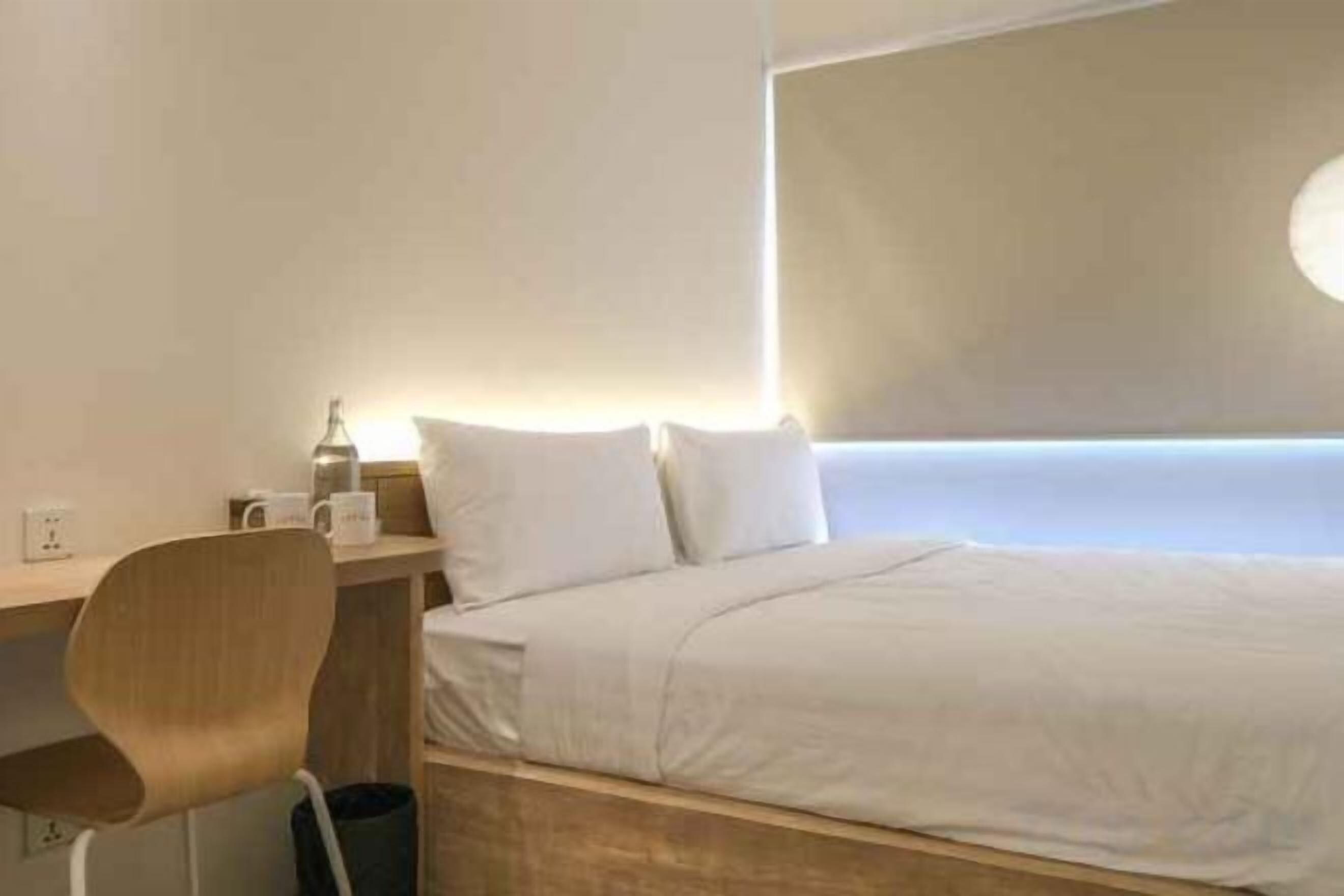 Quarto de hotel com cama, escrivaninha e cadeira.