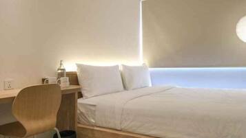 Quarto de hotel com cama, escrivaninha e cadeira.