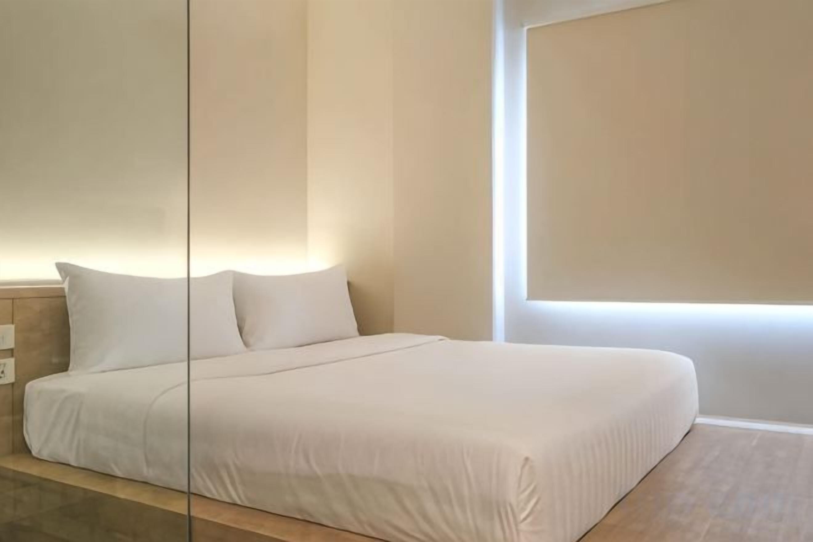 Una camera d'albergo con un letto grande, un comodino e una finestra che lascia entrare luce naturale.