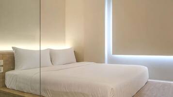 A hotel room with a large bed, a nightstand, and a window providing natural light.