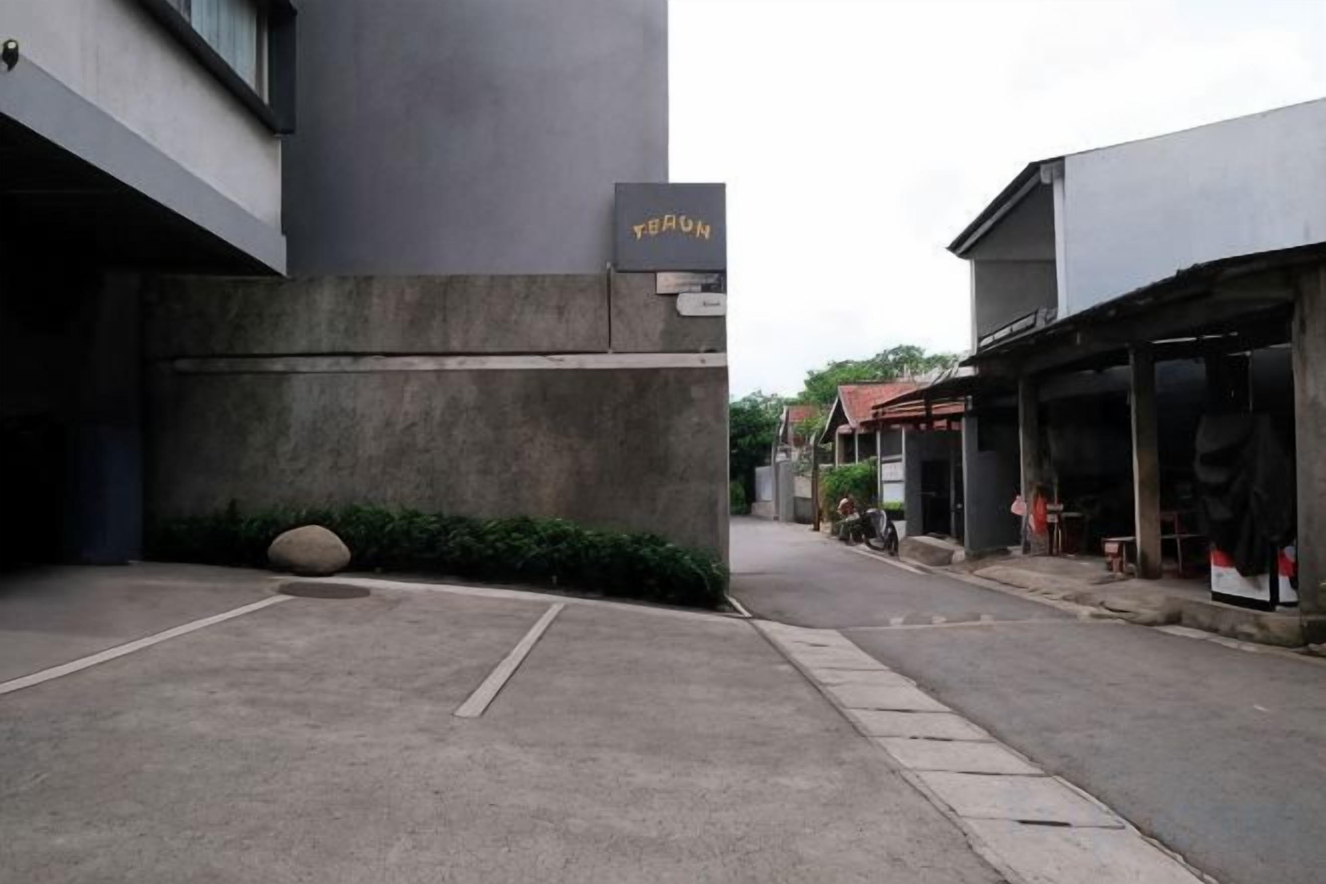 Una calle estrecha con un edificio identificado como 'TERON' a la izquierda, una tienda a la derecha y un cielo despejado.