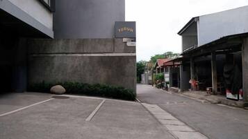 Una calle estrecha con un edificio identificado como 'TERON' a la izquierda, una tienda a la derecha y un cielo despejado.