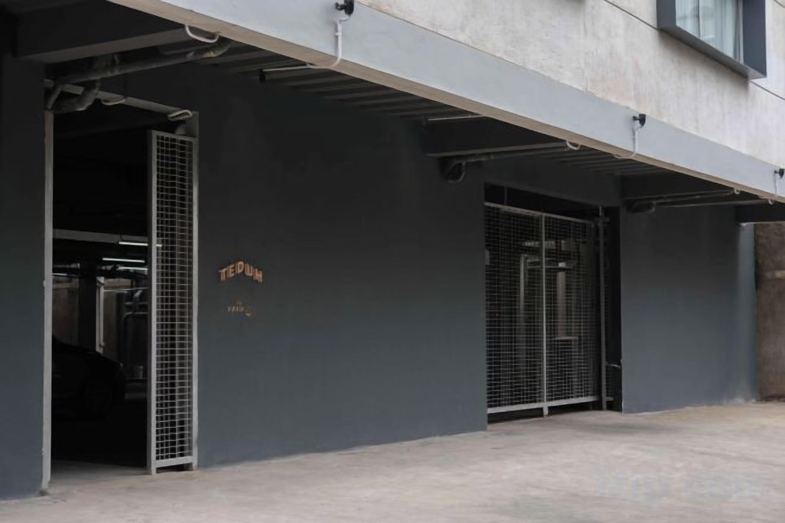 Un edificio con una puerta de garaje y un portón metálico, ambos abiertos.