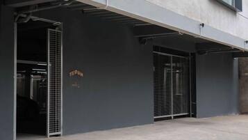 Un edificio con una puerta de garaje y un portón metálico, ambos abiertos.