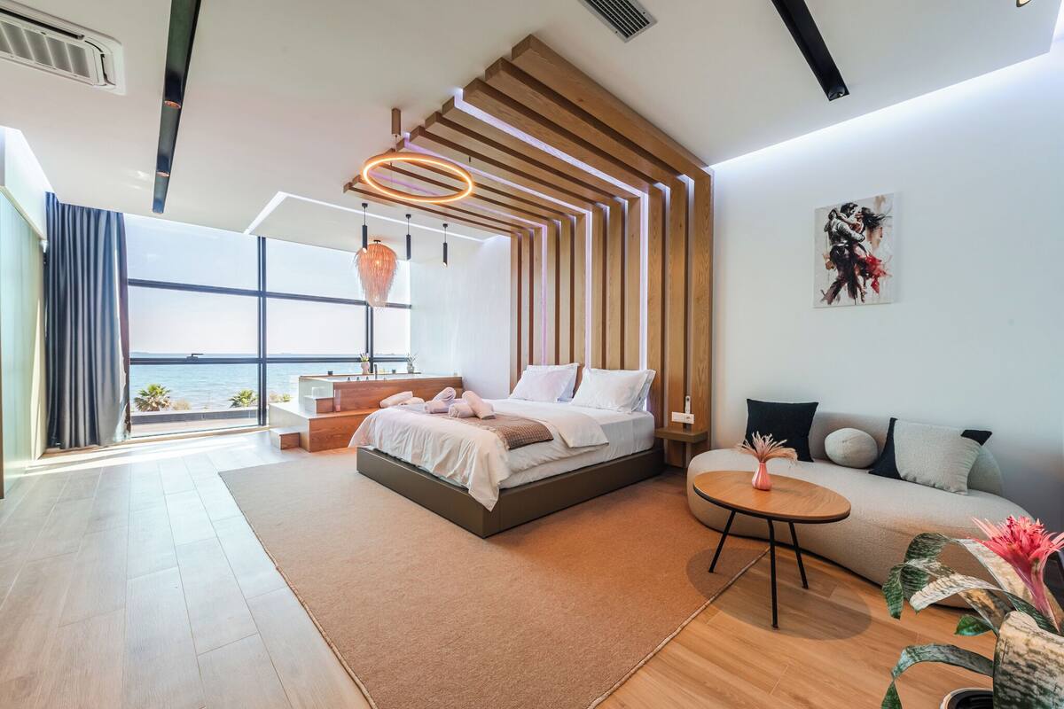 Een moderne slaapkamer met een groot bed, uitzicht op zee en een gezellige zithoek.