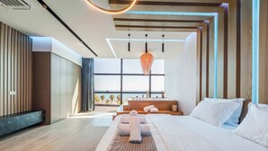 Un dormitorio moderno con una cama grande, un banco de madera y vista al mar.