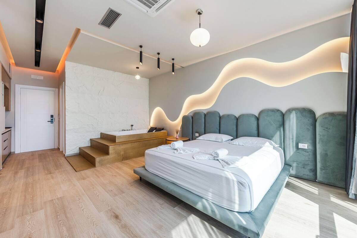 Een moderne hotelkamer met een groot bed, een inbouw bureau, een kaptafel en een trap naar een hoger niveau.